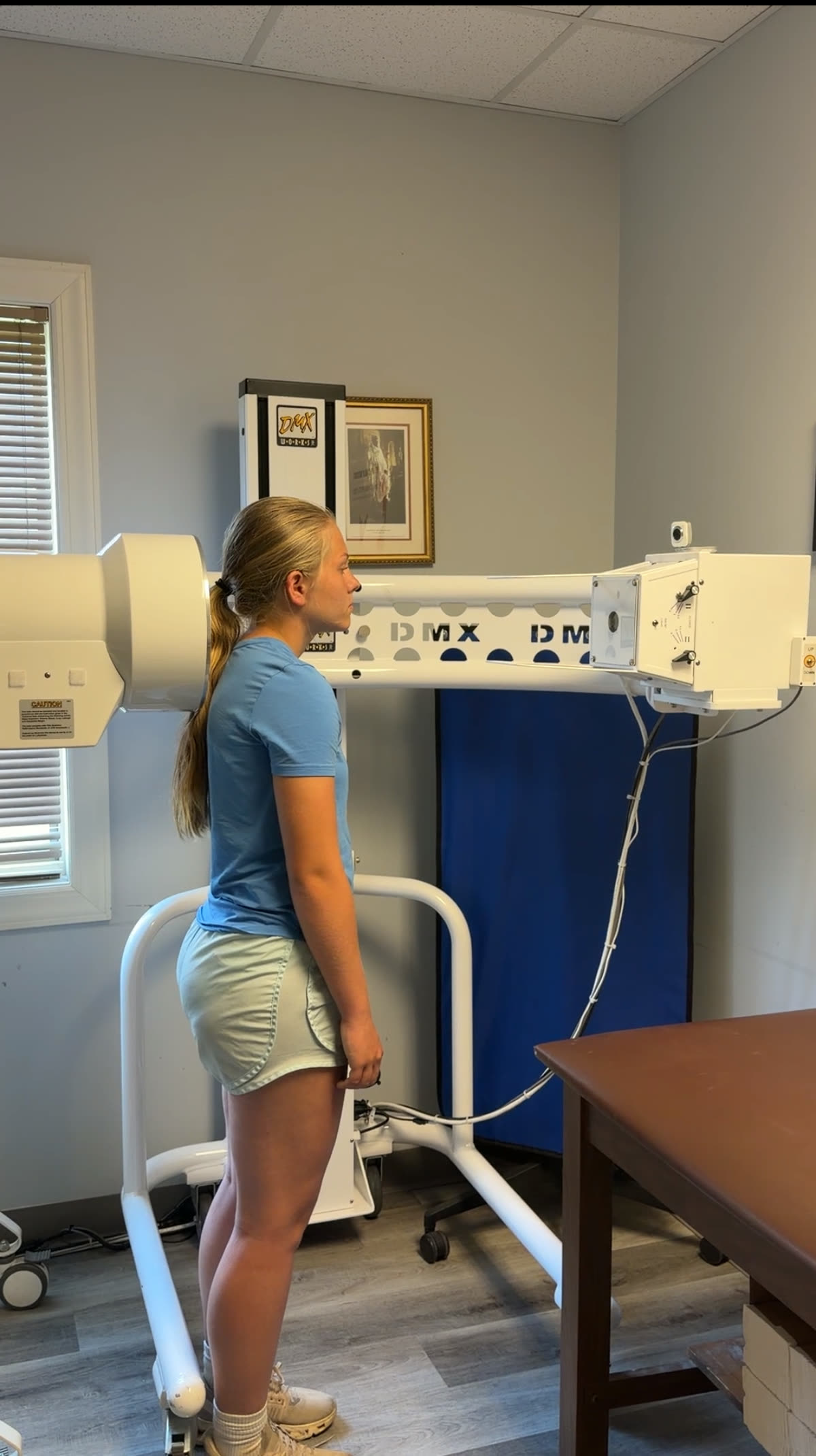 A patient standing upright between the arms of the Digital Motion X-ray machine